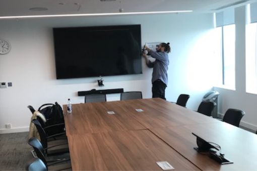 AV engineer installing audiovisual equipment in meeting room