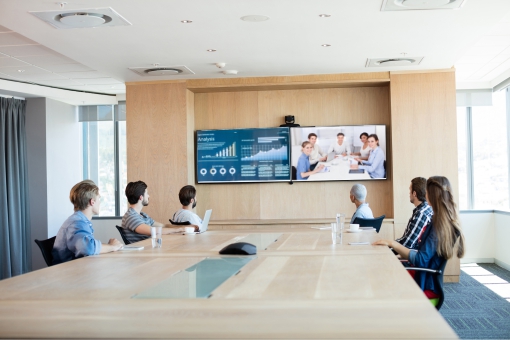 Team on a video conference call in a boardroom viewing two screens