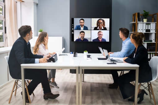 Team in a meeting room on a vide oconference call with remote workers