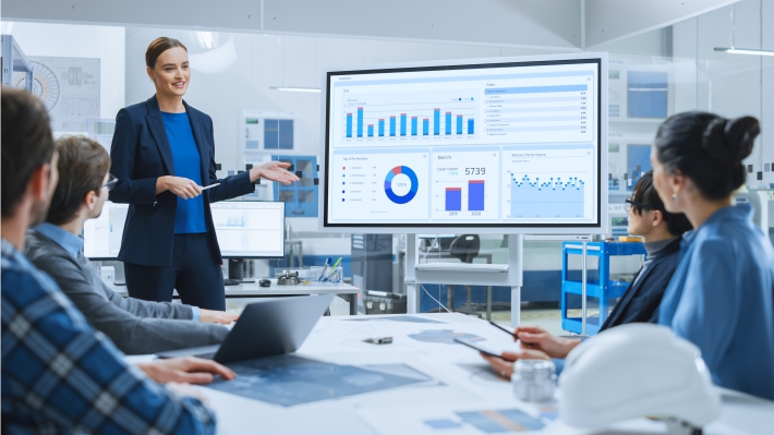 Woman presenting on an interactive white board to colleagues