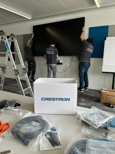Visually Connected installation team unboxing Crestron video conferencing equipment.
