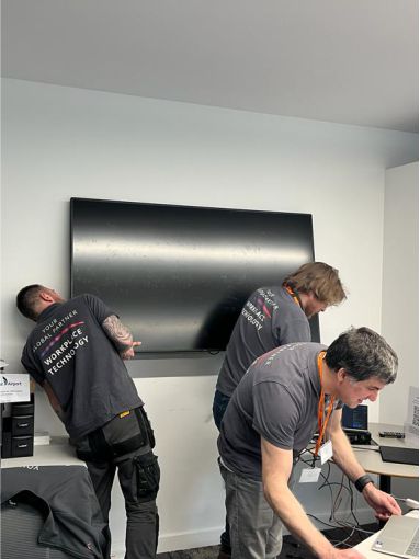 Installation team setting up display in meeting room