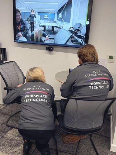 Installation team checking video camera and display connections in a large meeting room.