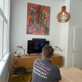 Technician installing video conferencing equipment at London creative agency.